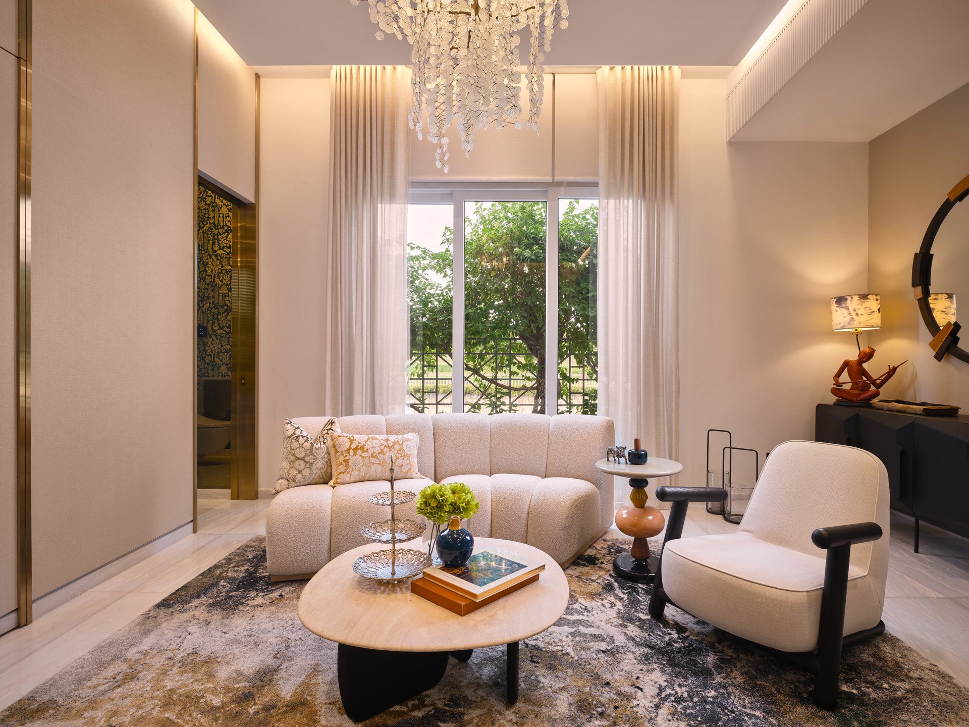 Double-height living room with pearl chandelier and bouclé sofa