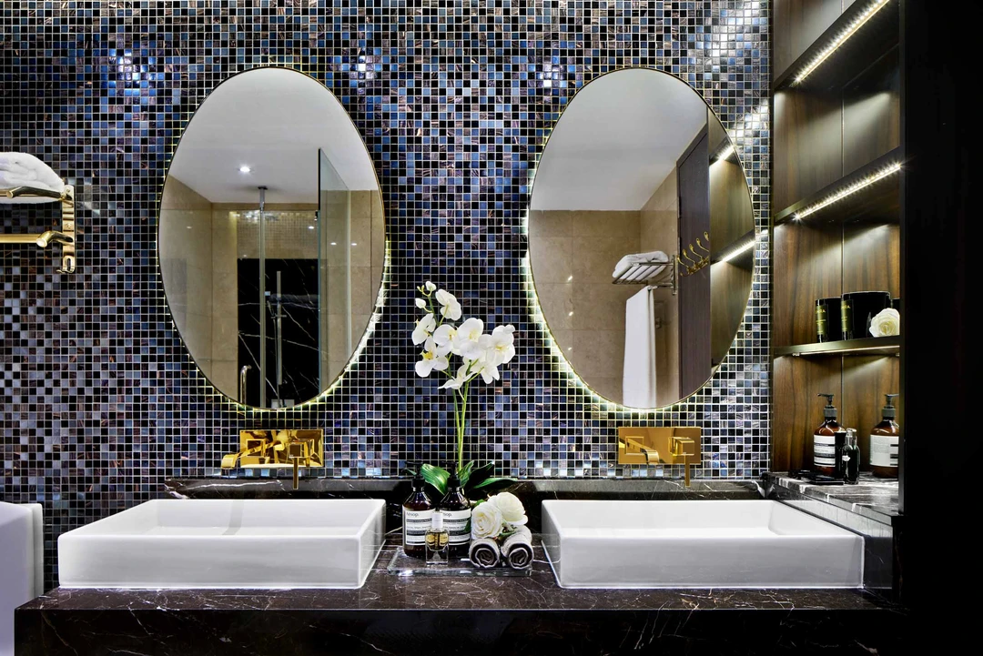 Luxury master bathroom with twin sinks, mirrors, and mosaic wall
