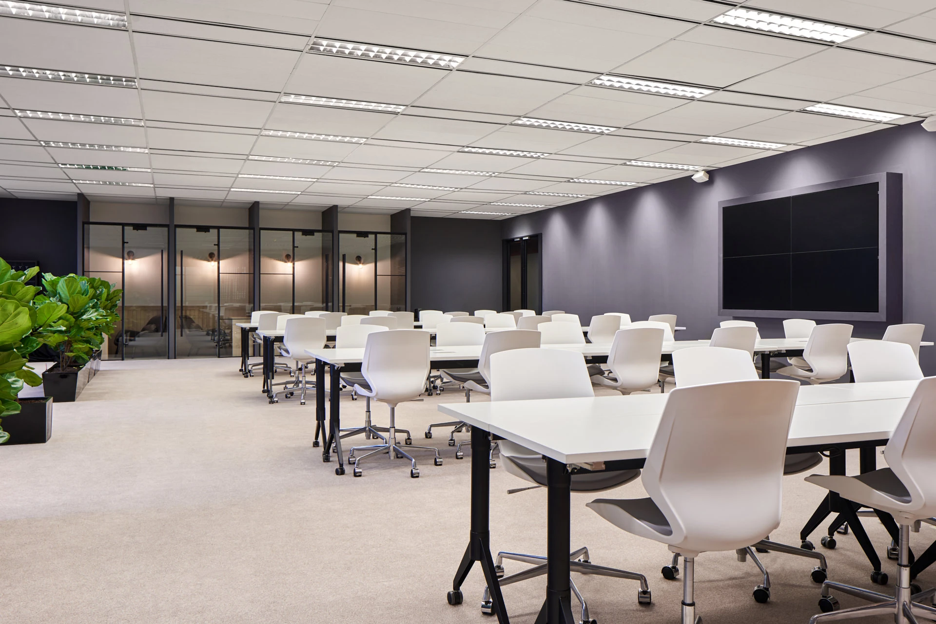 Training room with white flip-top tables and dark feature wall
