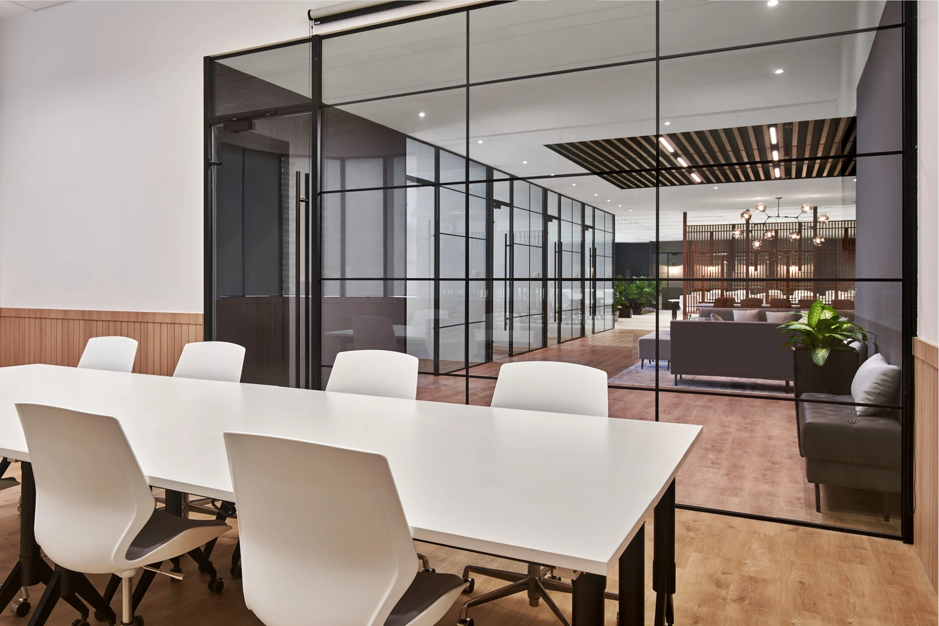 Glass-enclosed meeting room with Crittall partitions and white conference table