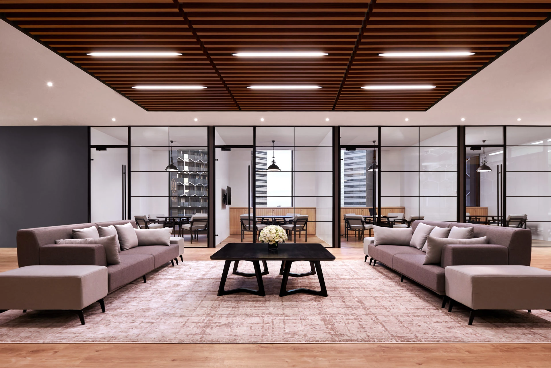 Executive lounge with floating timber ceiling and grey sectional sofas