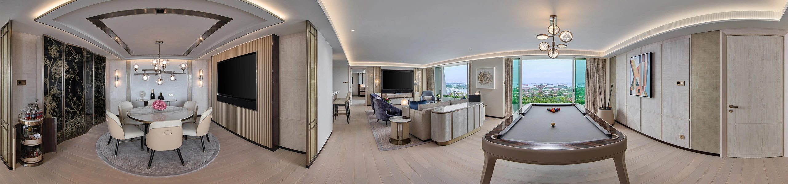 Panoramic view of a luxury hotel suite entertainment room with pool table, round dining table, large wall-mounted TV, lounge seating, and harbor views.