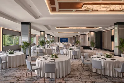 METT Singapore Grand Ballroom viewed from the side with cluster banquet tables, stage screen, coffered ceiling lights, and event seating
