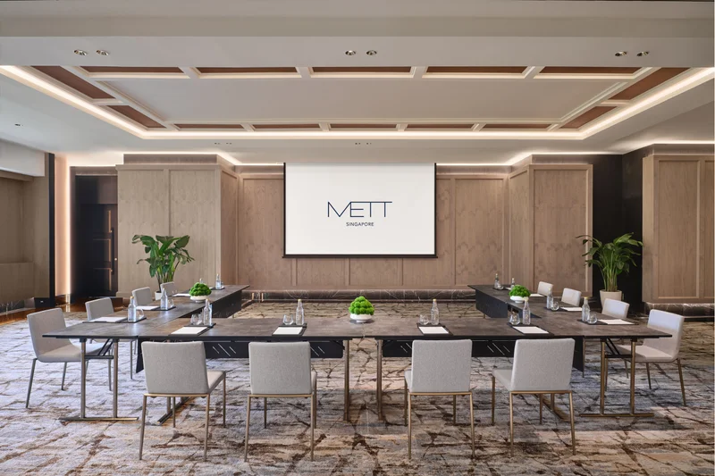 METT Singapore Junior Ballroom U-shape meeting setup with presentation screen, wood wall panelling, potted plants, and hospitality event seating