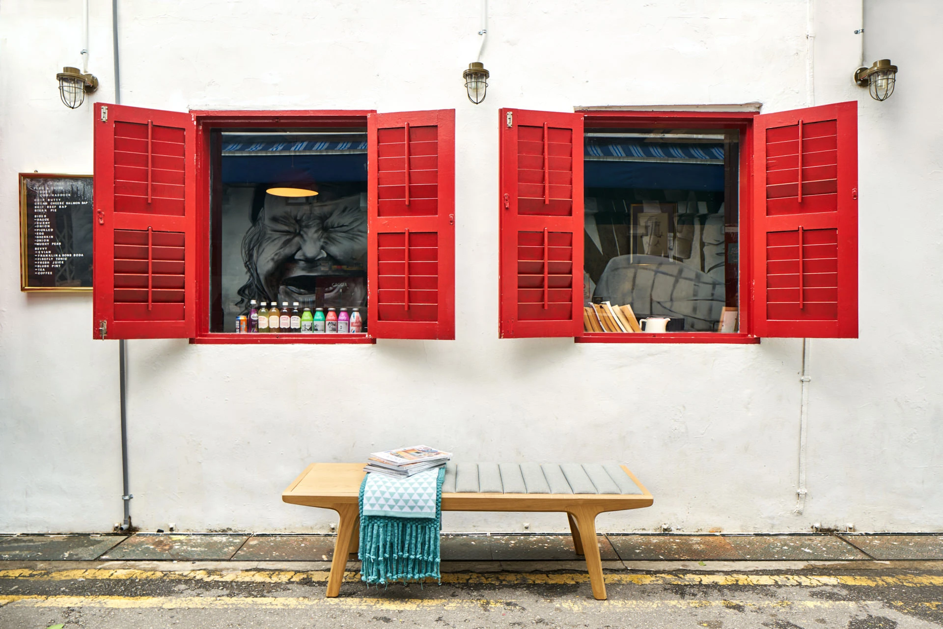 Timber bench beneath red shuttered windows on white plaster wall