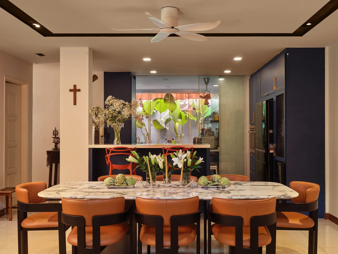 Serangoon Chuan Drive dining room by Nidhi Jain with marble dining table, orange chairs, staircase and leafy garden backdrop