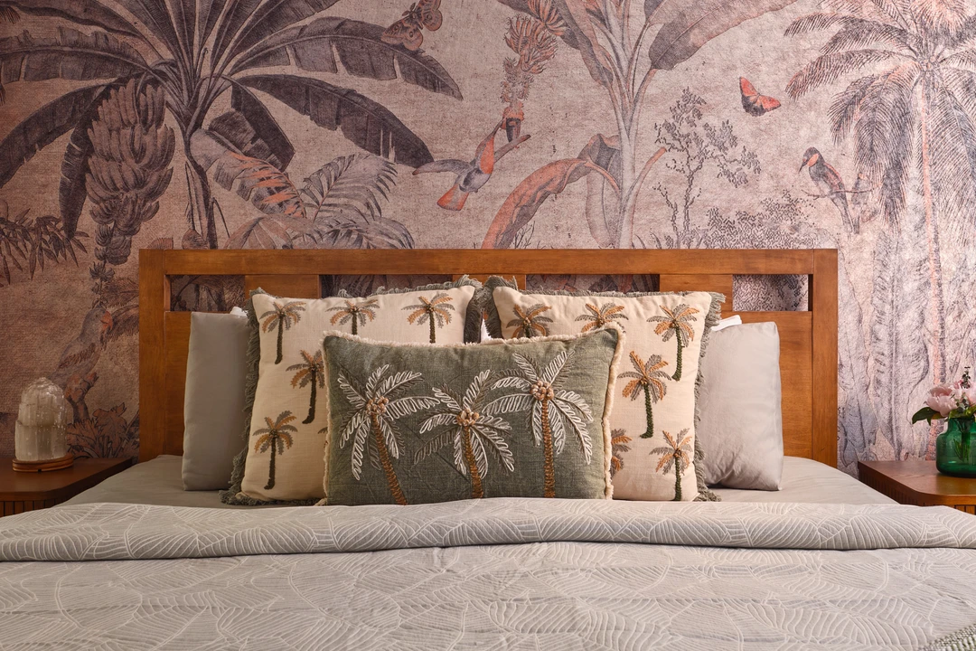 Serangoon Chuan Drive bedroom detail by Nidhi Jain with palm mural, timber headboard, layered pillows and bedside styling