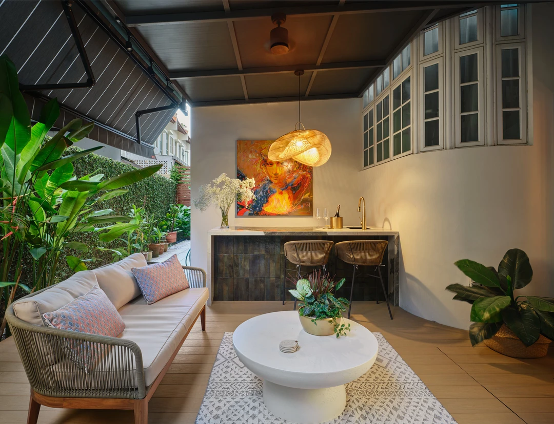Covered terrace at Serangoon Chuan Drive by Nidhi Jain with rattan sofa, console bar, pendant light and tropical planting