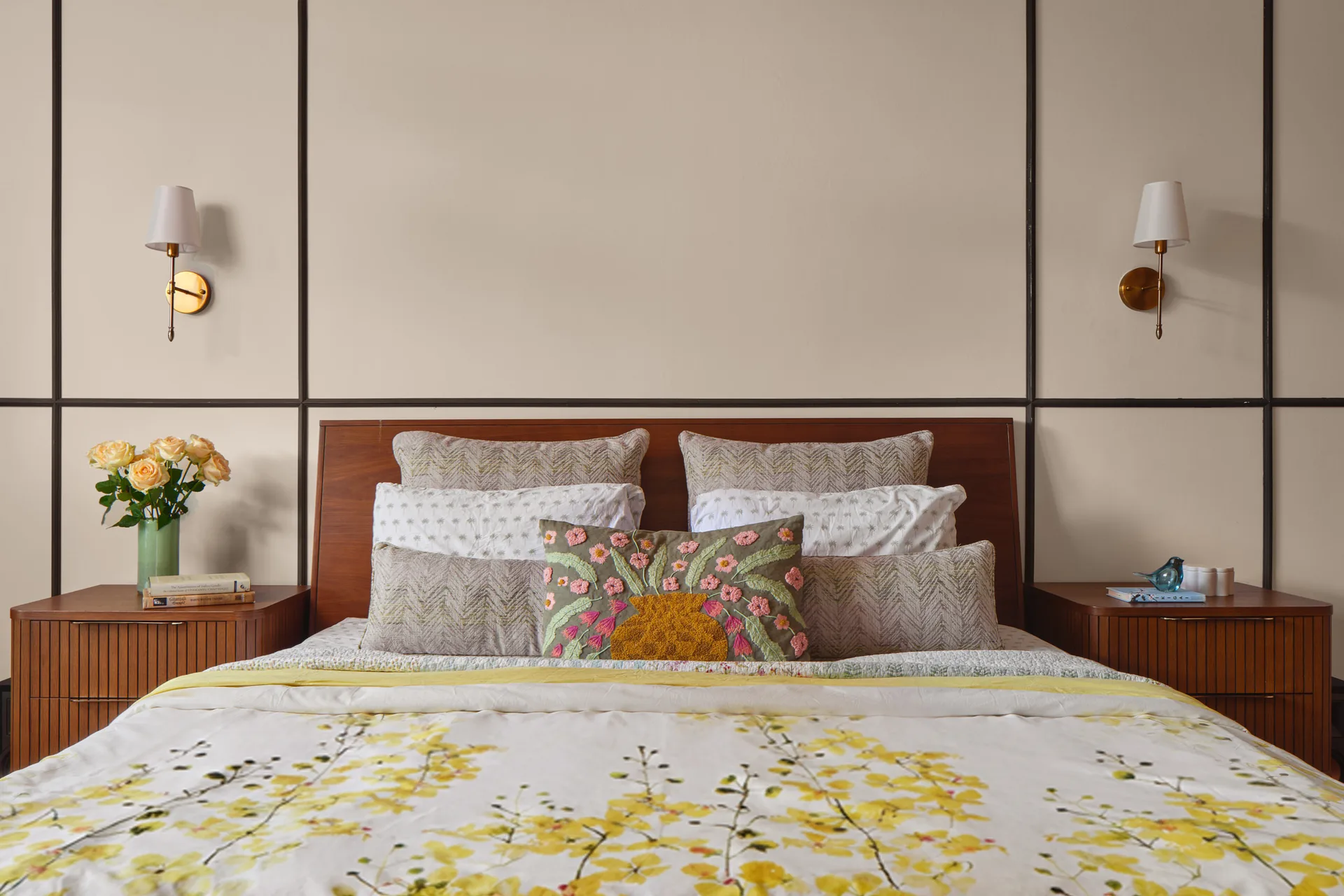 Bayshore bedroom bed styling by Nidhi Jain with wall sconces, floral bedding and tall paneled headboard wall, crop detail