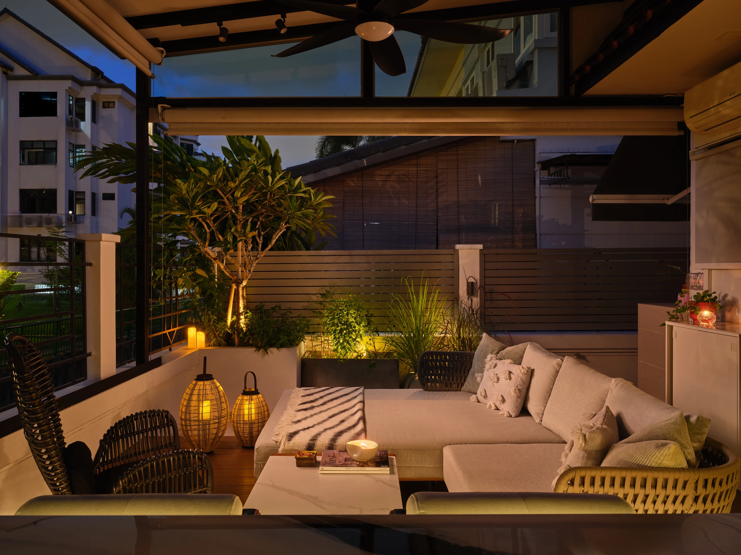 Covered rear lounge with plush cushions, string lights and tropical planting
