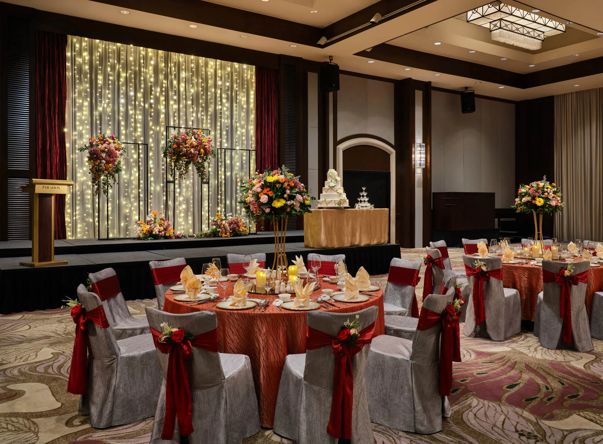 Chinese wedding reception in red and gold with tiered cake and floral stands - Paradox Singapore function room photography