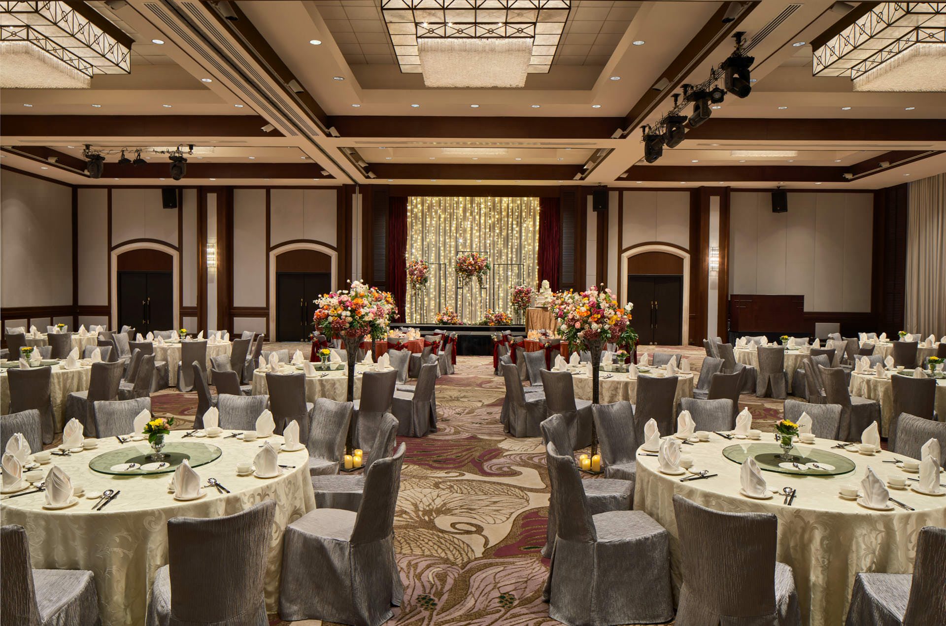 Wedding banquet with ivory linens, floral aisle and fairy-light backdrop - Paradox Singapore ballroom photography