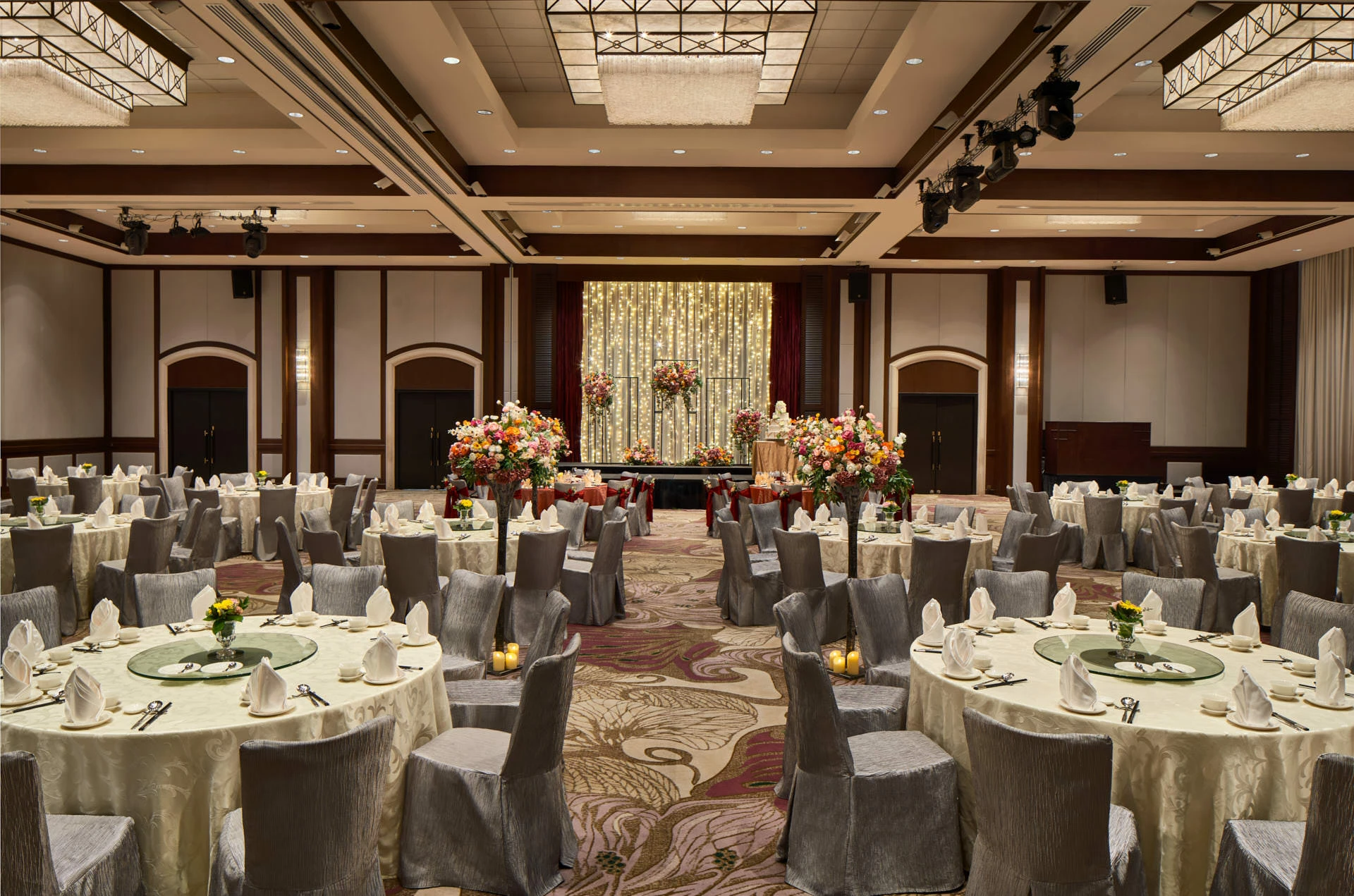 Wedding banquet with ivory linens, floral aisle and fairy-light backdrop - Paradox Singapore ballroom photography