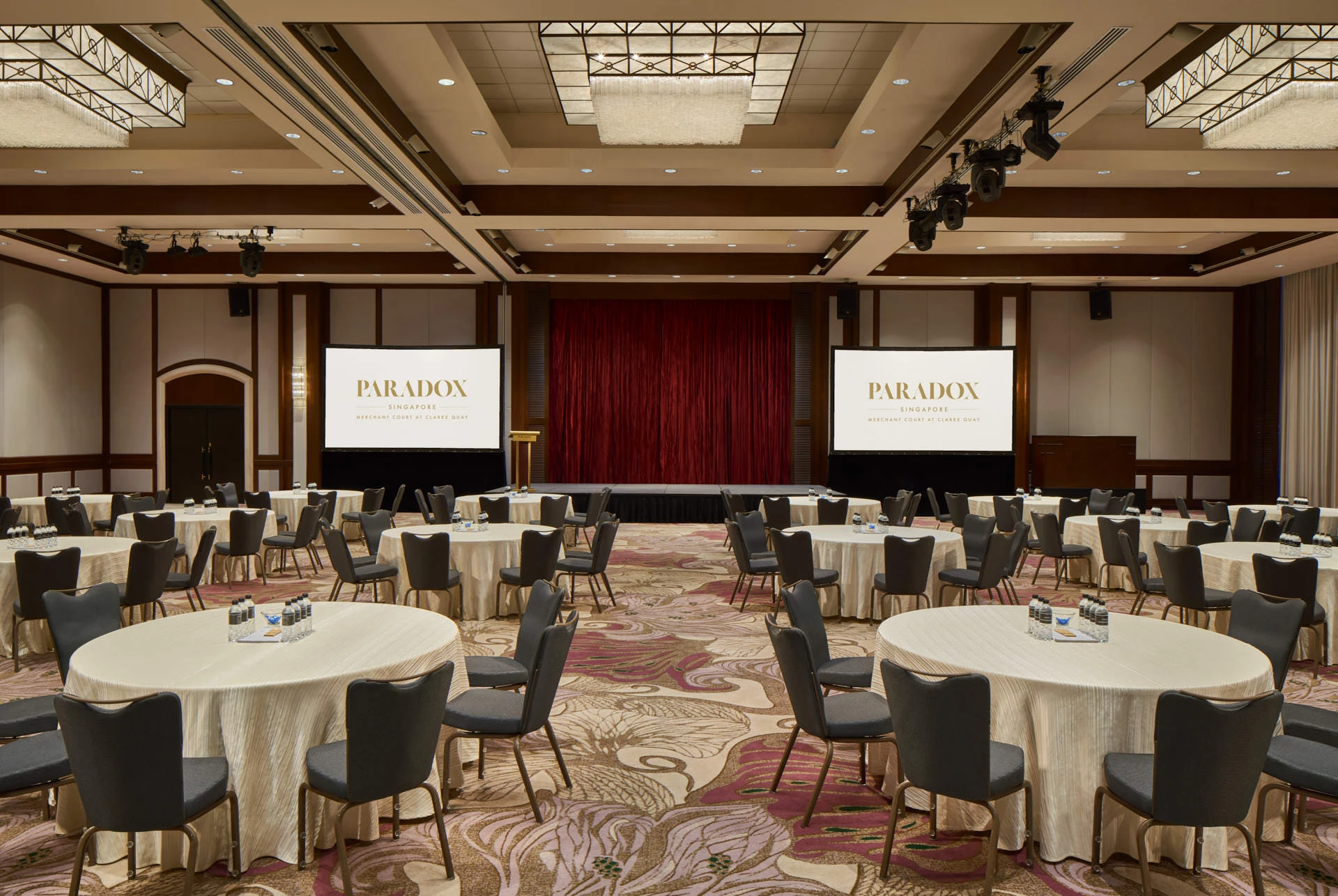 Corporate conference in cabaret style with dual screens and stage lighting - Paradox Singapore ballroom photography