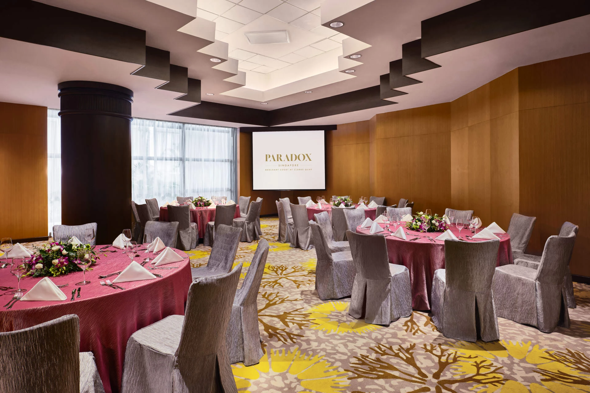 Dinner event with magenta linens, floral centrepieces and tiered ceiling - Paradox Singapore function room photography
