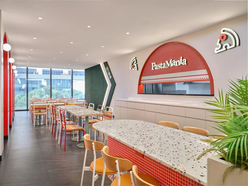 Terrazzo communal tables with mosaic bases and green planter dividers at PastaMania Jem