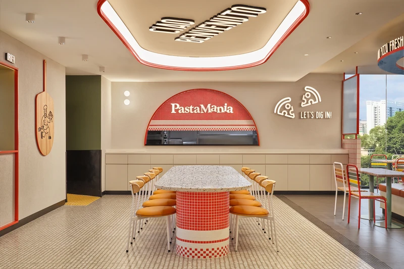 Communal dining beside checkered mosaic kitchen pass with branded signage at PastaMania Northpoint