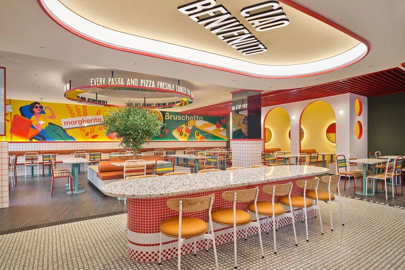 Panoramic view of dining room with olive tree, arched booths and mural wall at PastaMania Northpoint