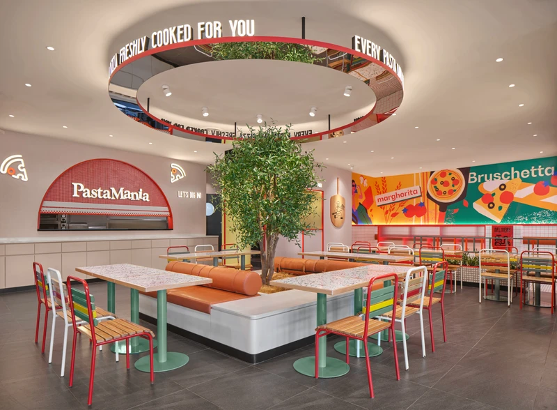 Open-plan dining hall with live olive tree, mirrored ceiling ring and terrazzo tables at PastaMania Sengkang