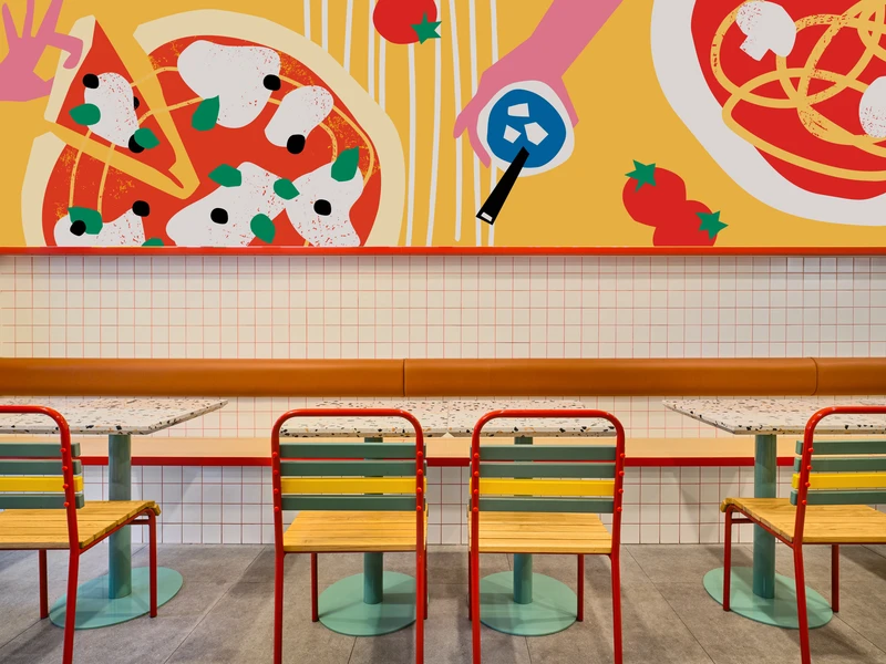 Banquette wall with pizza mural, terrazzo tables and red tubular chairs at PastaMania Tampines