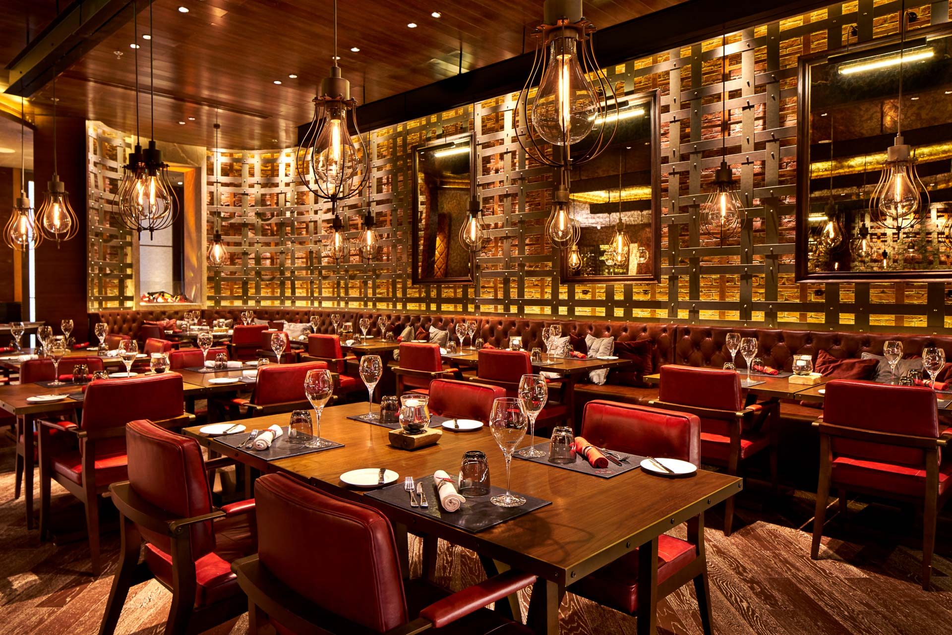 Dining room with red leather chairs, cage pendants and woven metal wall