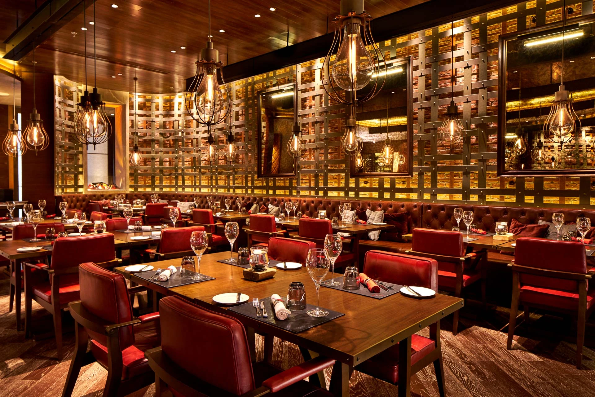 Dining room with red leather chairs, cage pendants and woven metal wall