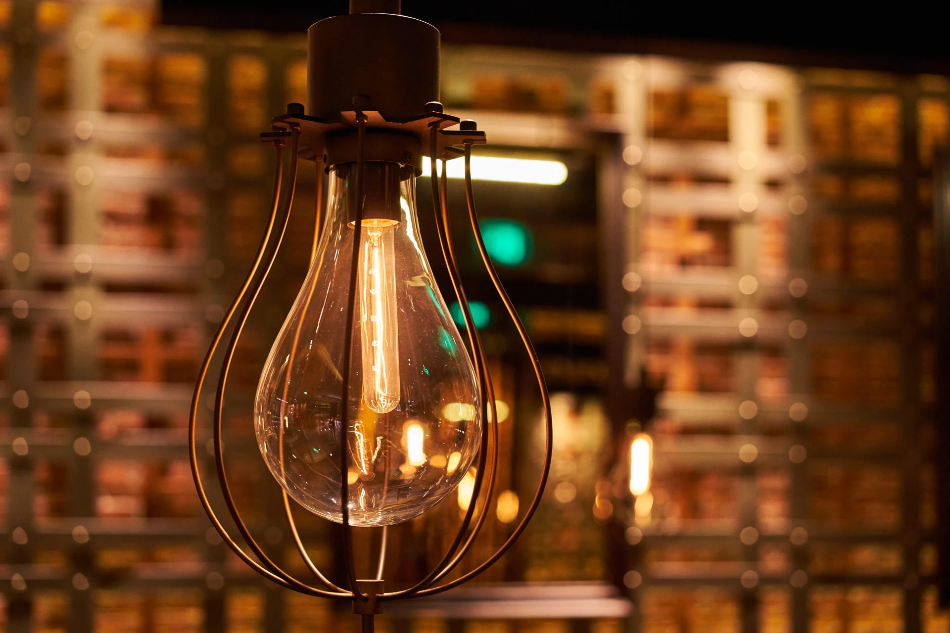 Close-up of cage pendant filament against golden lattice wall