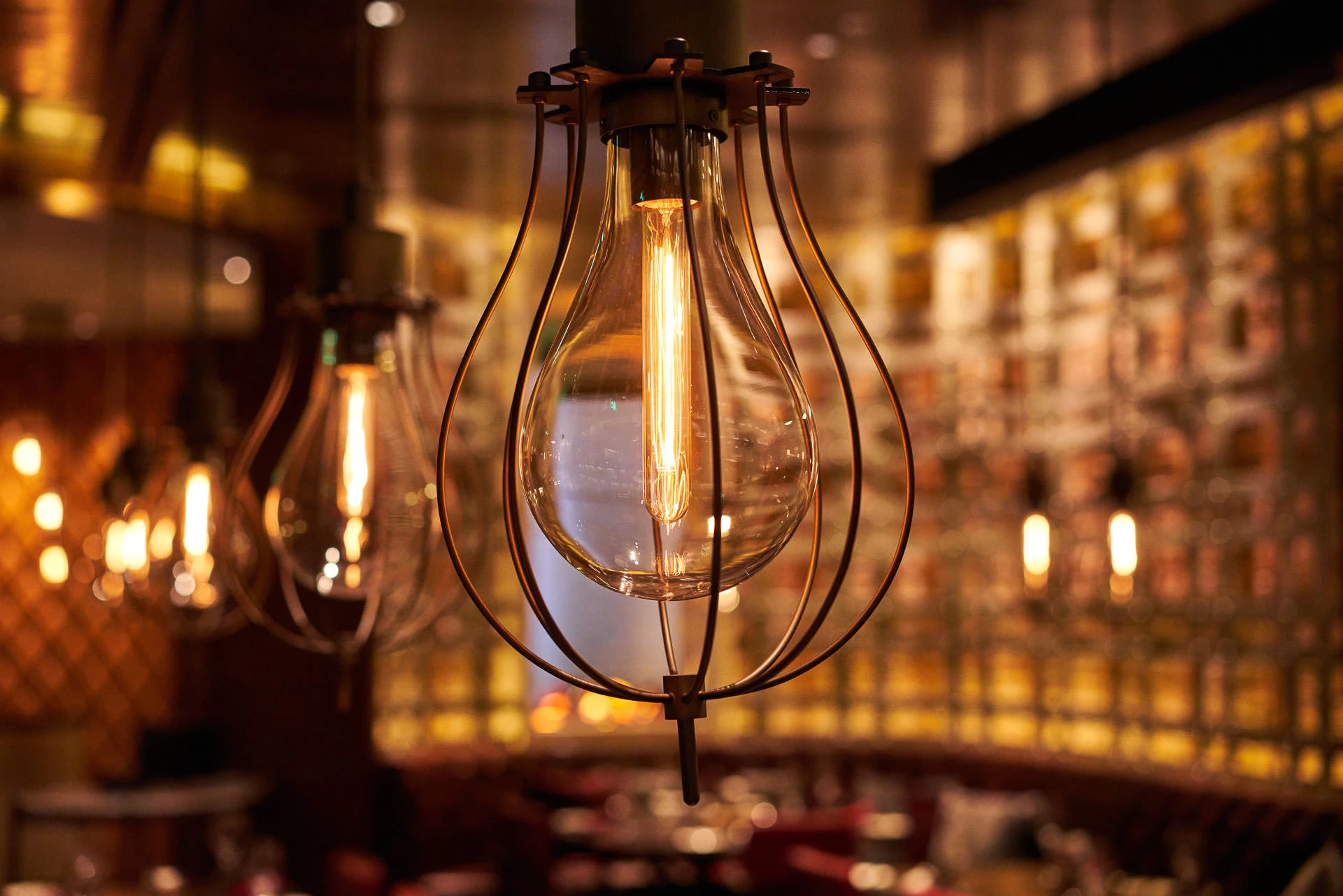 Teardrop cage pendant light detail with warm amber bokeh