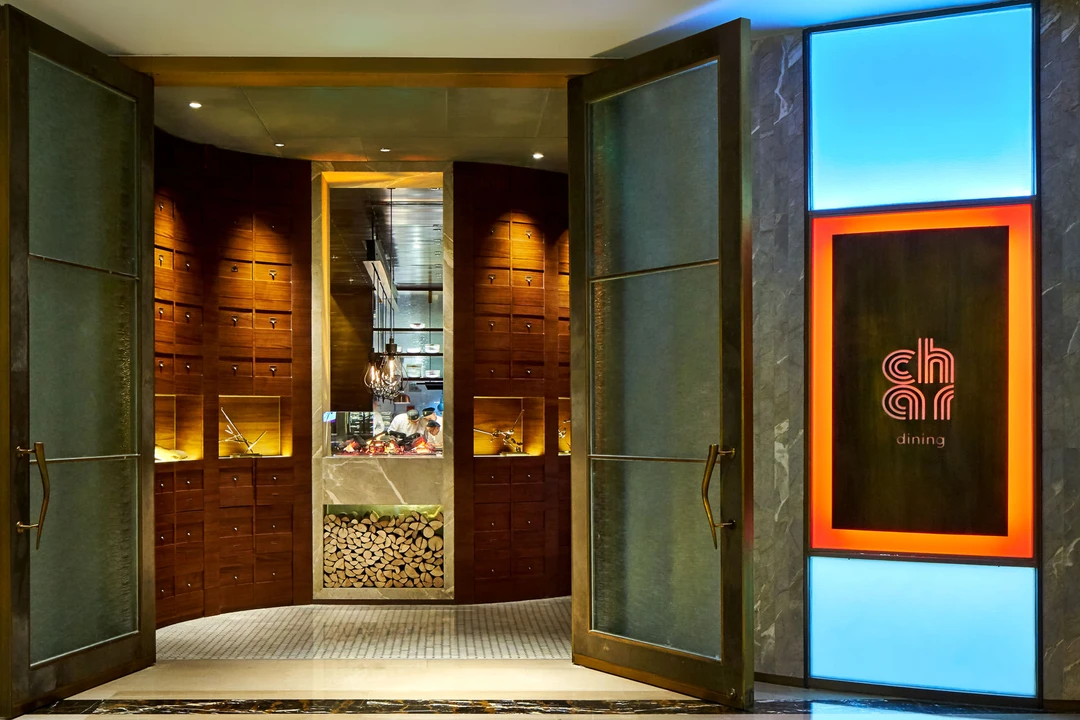 Bronze doors and neon logo against dark marble facade