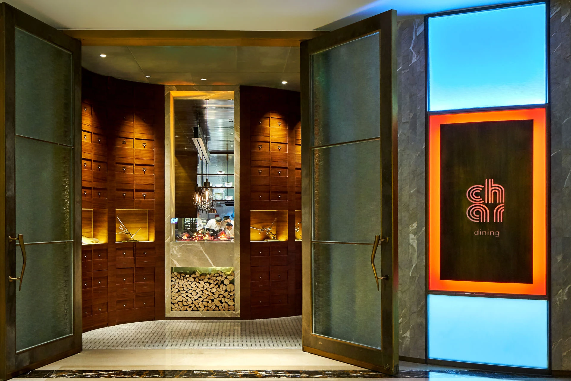 Bronze doors and neon logo against dark marble facade