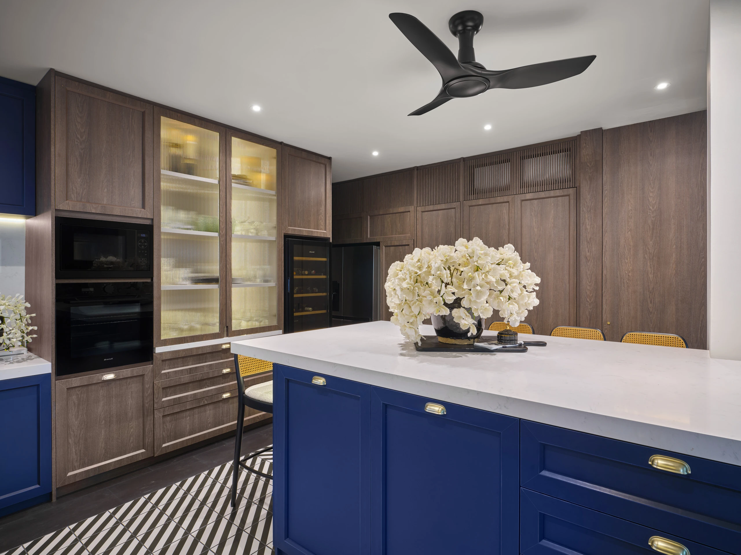Kitchen with navy blue island, white upper cabinets and timber floor