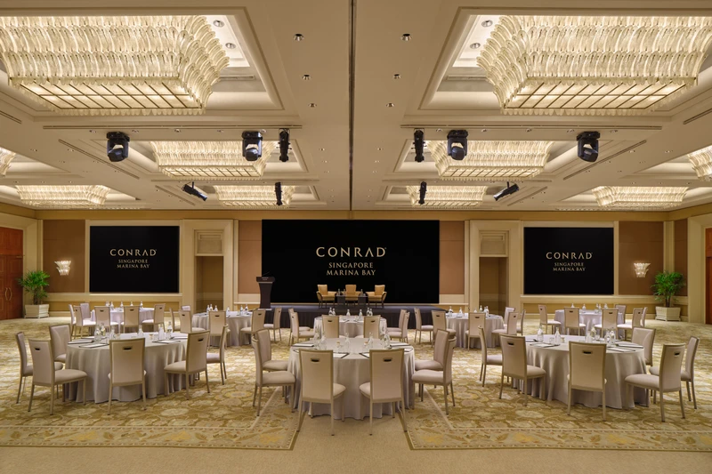 Conrad Singapore Marina Bay Grand Ballroom in North South cluster setup with crystal ceiling lights, stage screens and patterned carpet