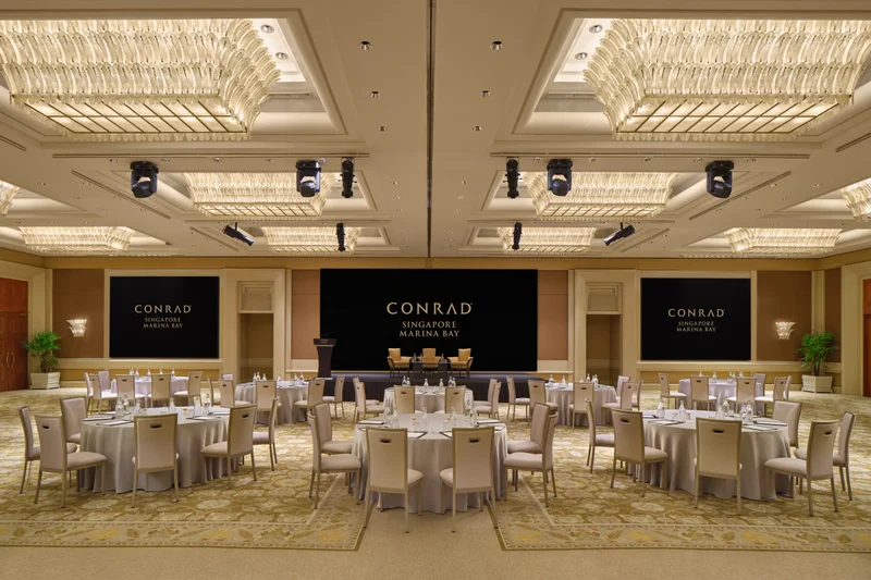 Conrad Singapore Marina Bay Grand Ballroom in North South cluster setup with crystal ceiling lights, stage screens and patterned carpet