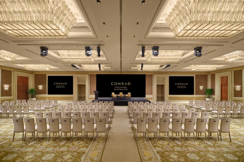 Conrad Singapore Marina Bay Grand Ballroom in North South theatre setup with crystal ceiling lights, stage screens and patterned carpet