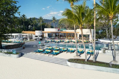 Tropical resort pool area with teal sun loungers, striped umbrellas and palm trees