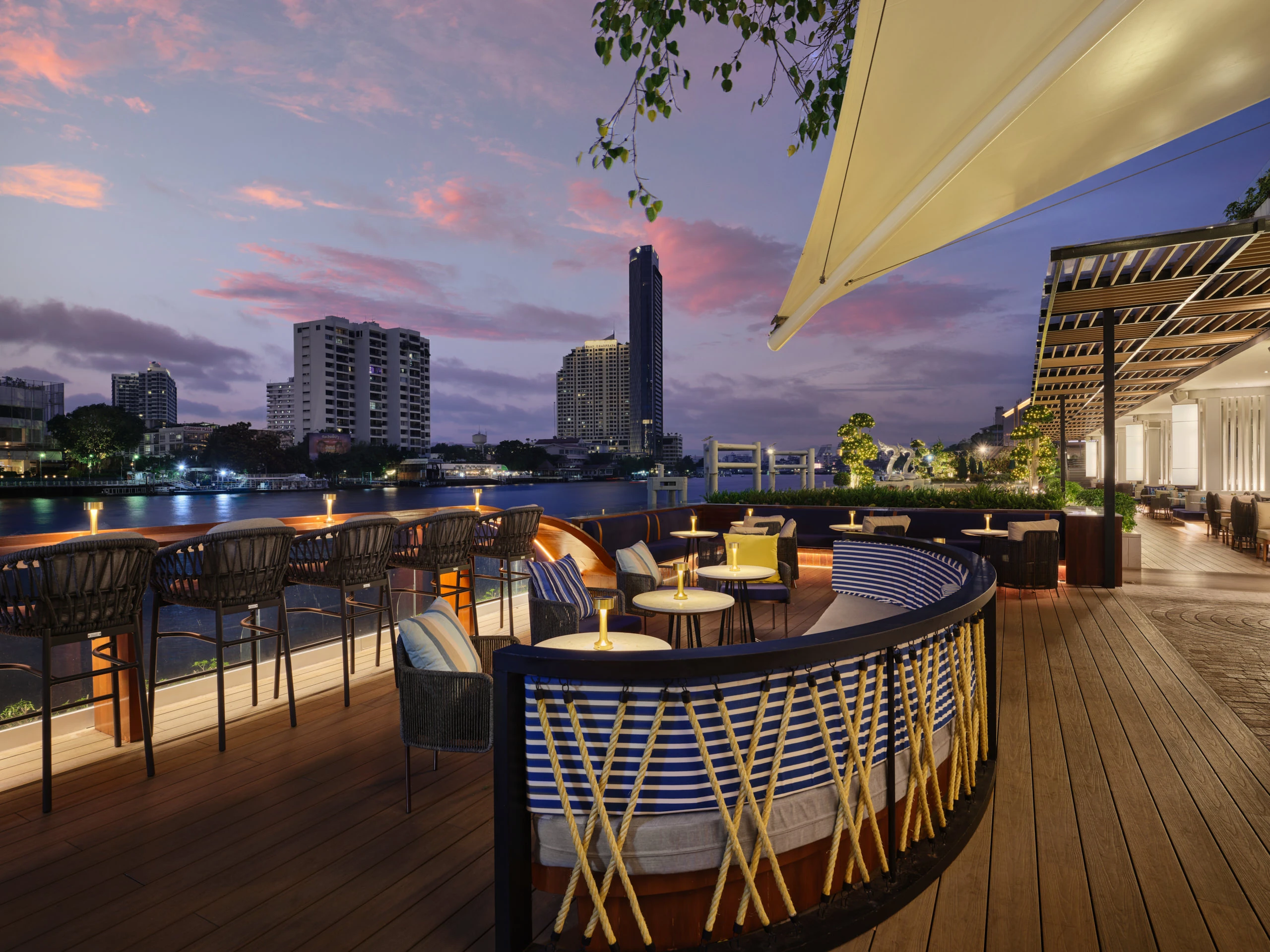Waterfront lounge with nautical banquettes and sunset skyline — Siam Yacht Club Bangkok hospitality photography