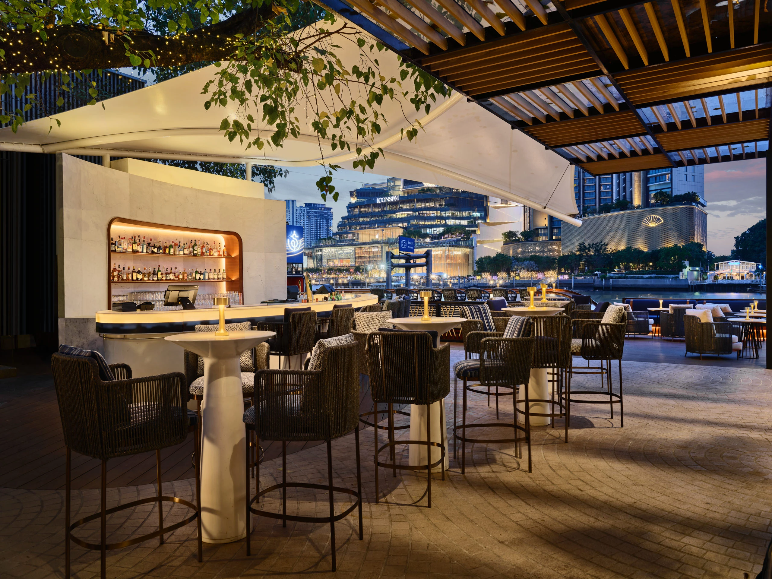 Twilight cocktail bar with rope stools and city skyline across river — Siam Yacht Club Bangkok hospitality photography