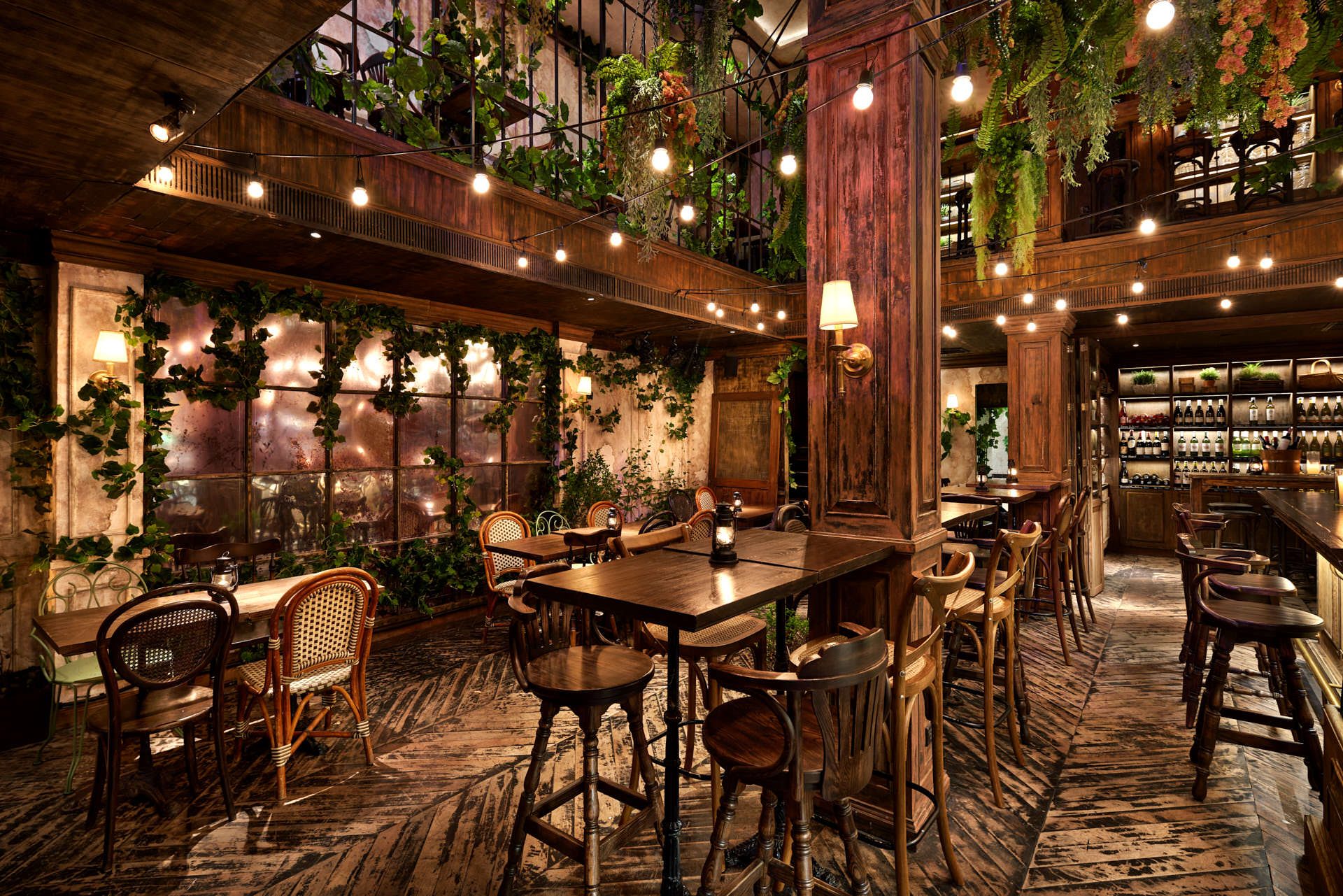 Double-height atrium with ivy walls, mirrored panels and rattan chairs