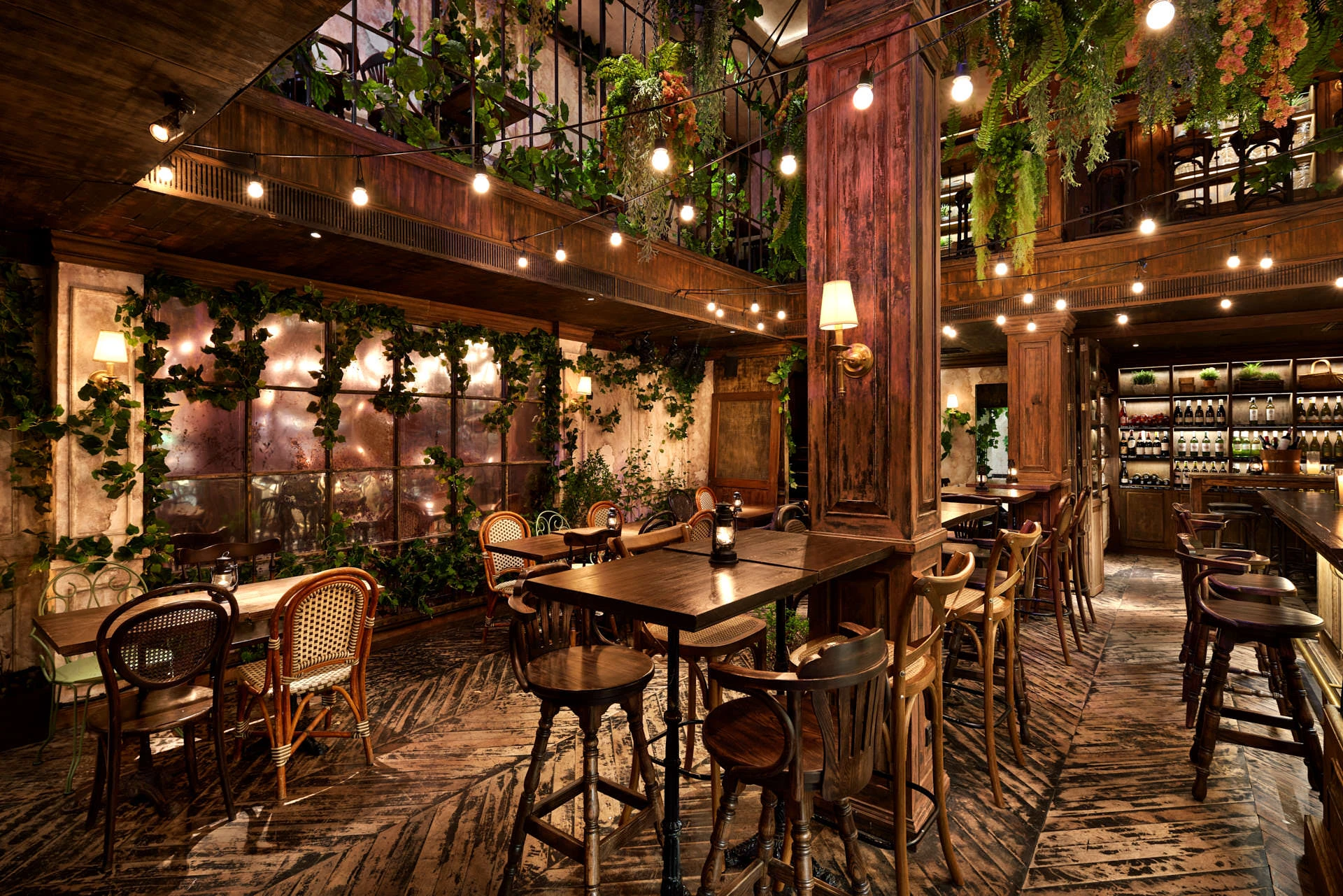 Double-height atrium with ivy walls, mirrored panels and rattan chairs