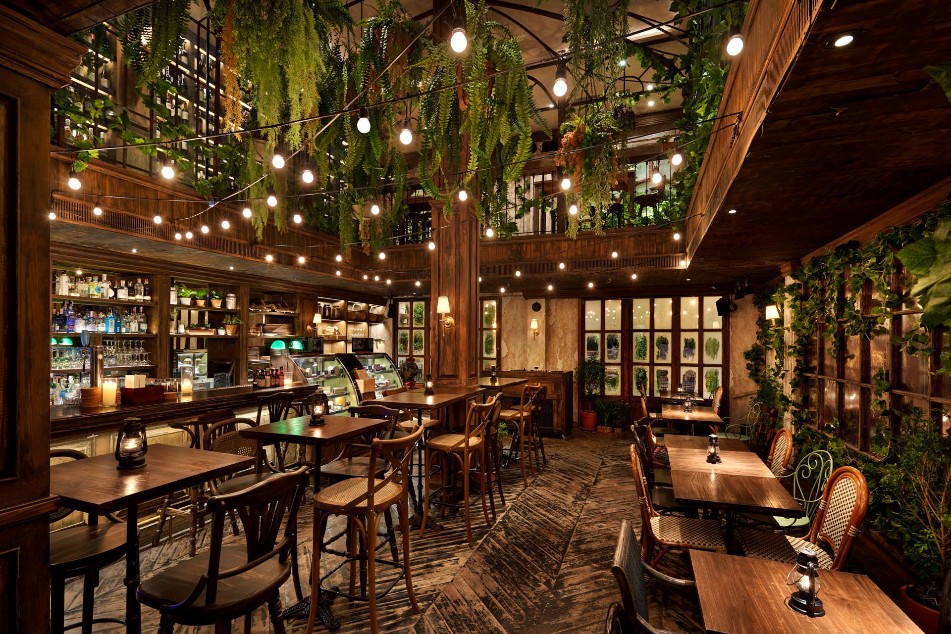 Dining room with bistro chairs, festoon lights and vine-covered mezzanine