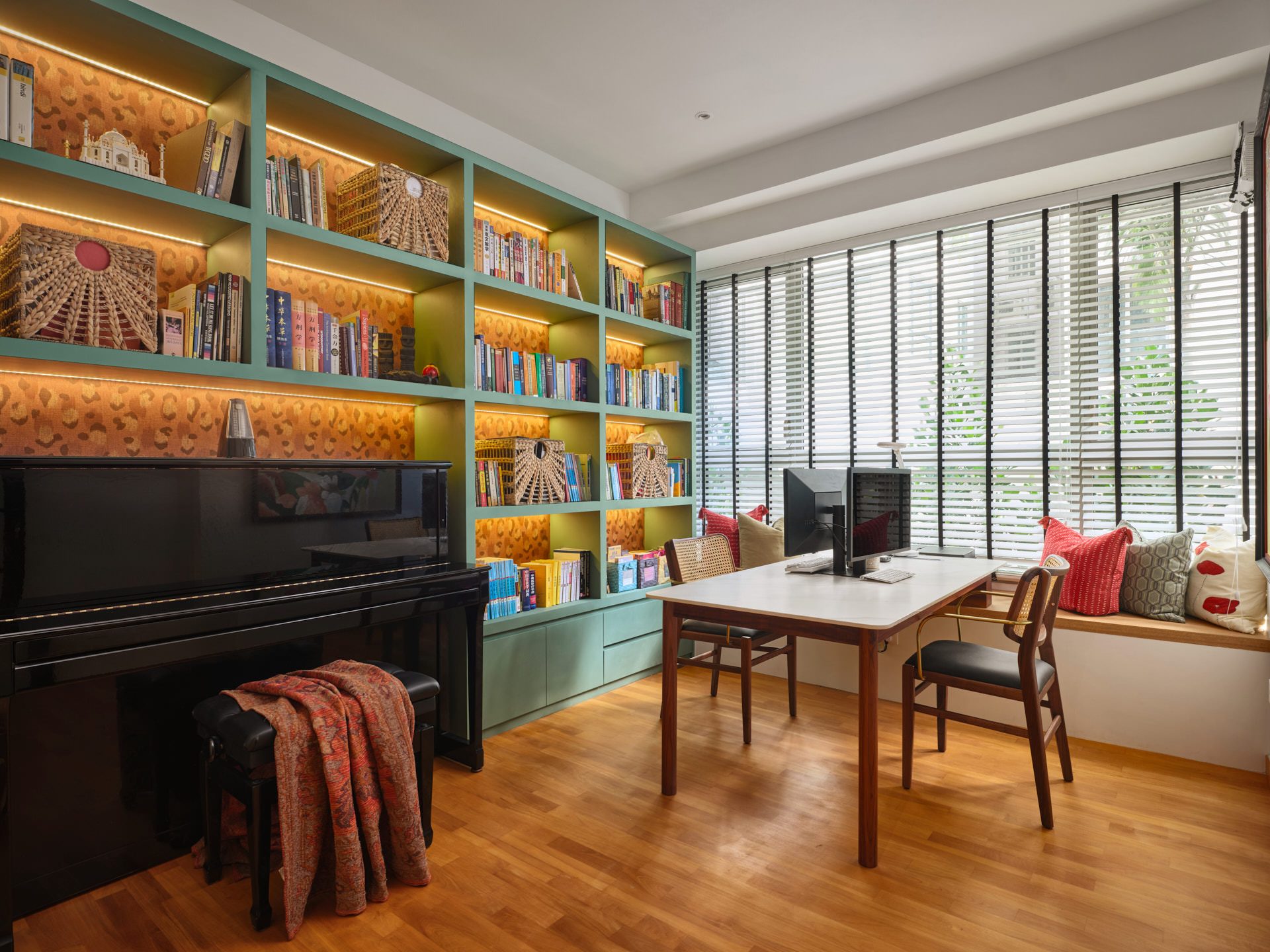 Study with teal bookshelves, gold paisley wallpaper and upright piano