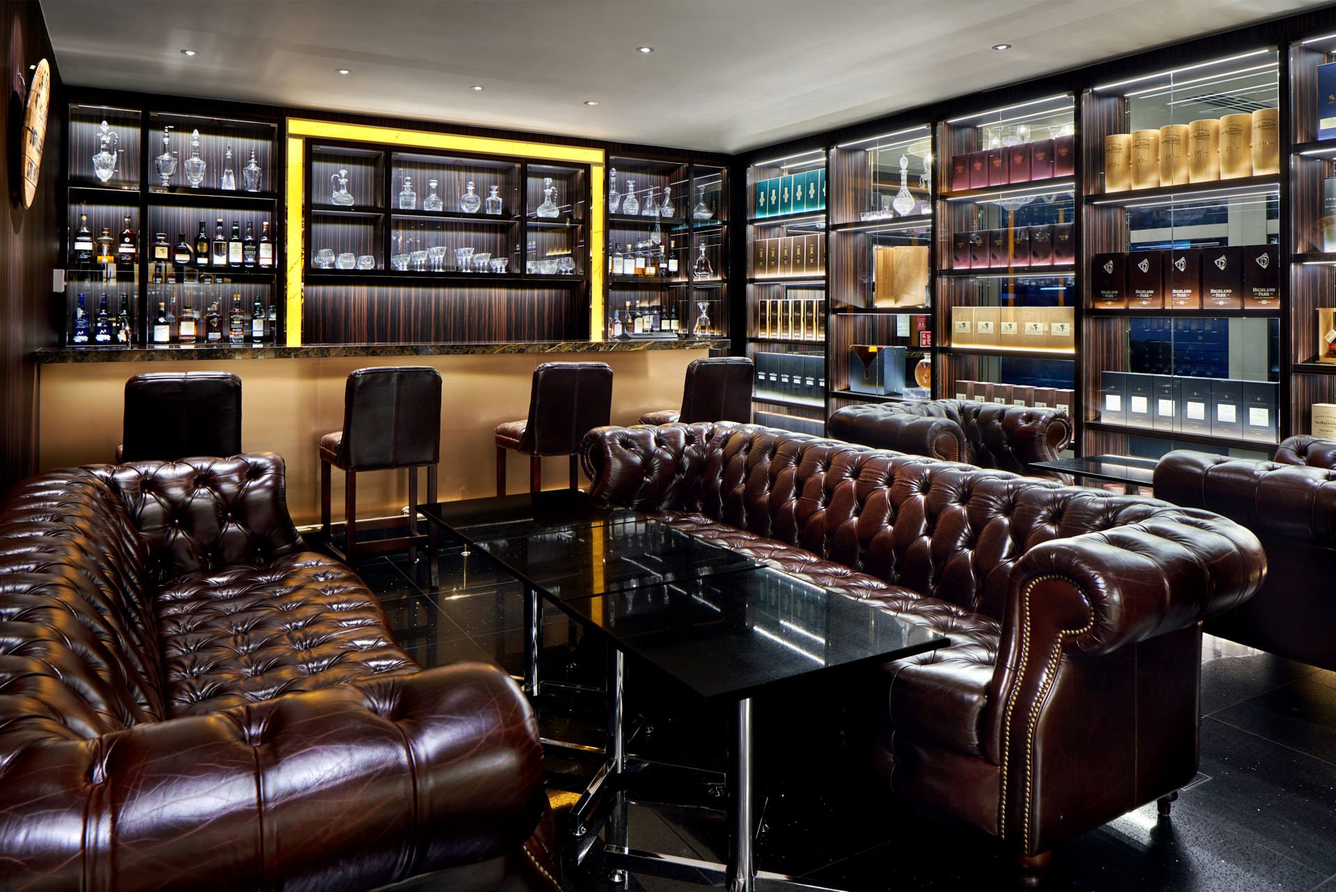 Whisky bar with Chesterfield sofas, gold bar front and backlit decanters
