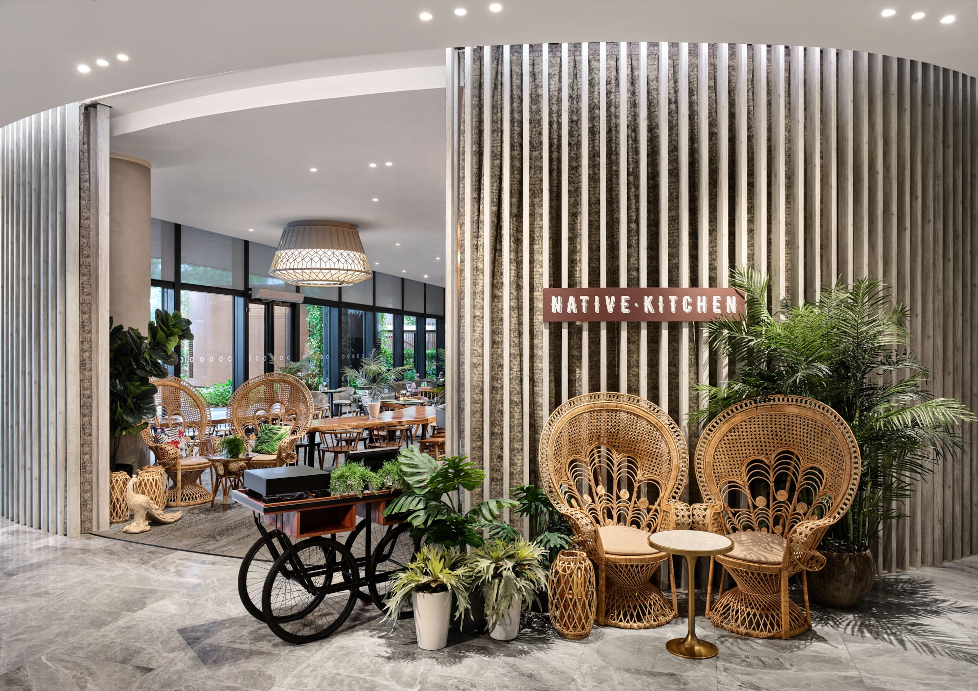 Native Kitchen signage with timber slats and peacock rattan chairs — Village Hotel Sentosa restaurant photography