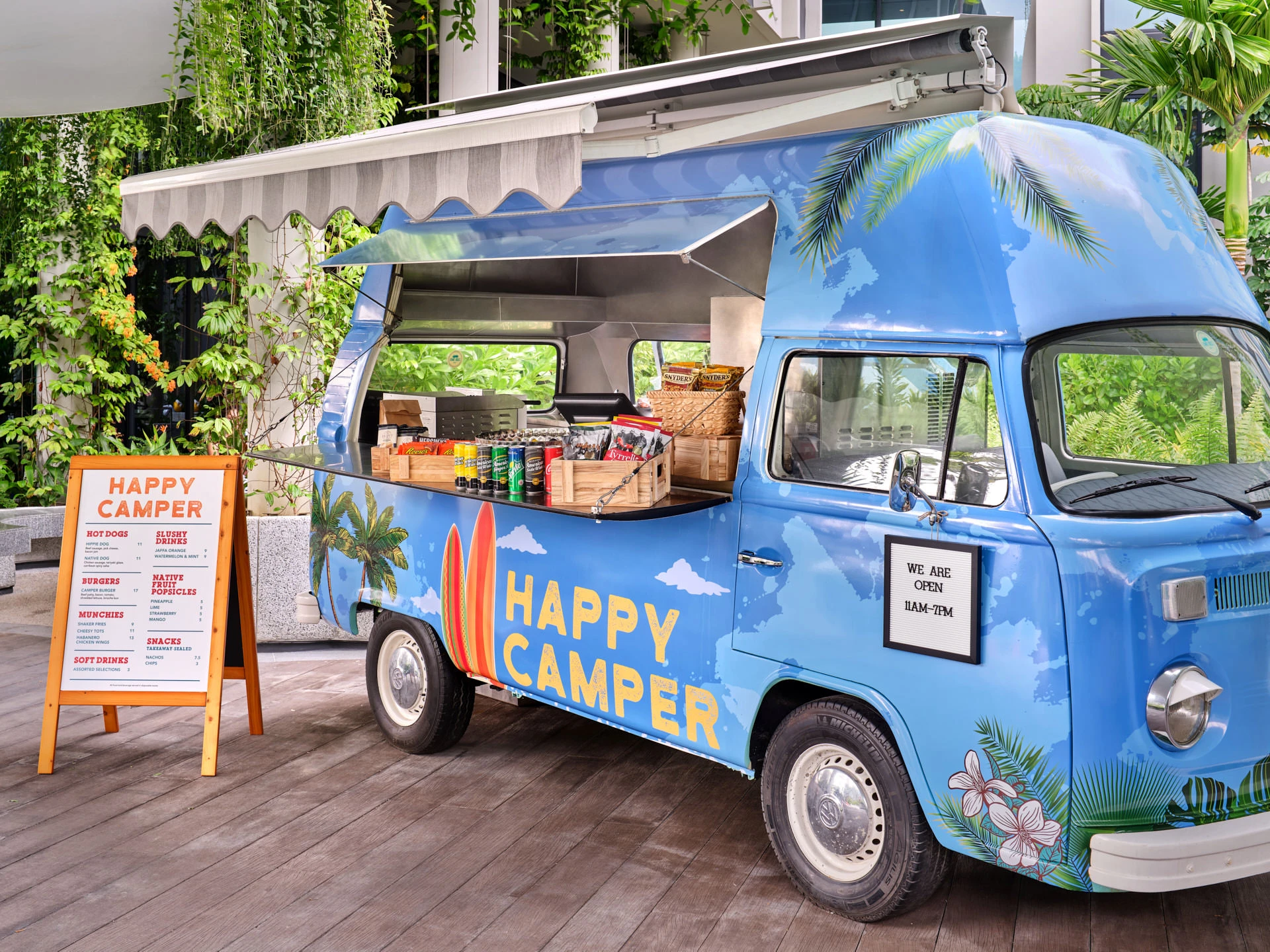 Happy Camper food truck serving hatch with snack baskets and tropical greenery — Village Hotel Sentosa photography