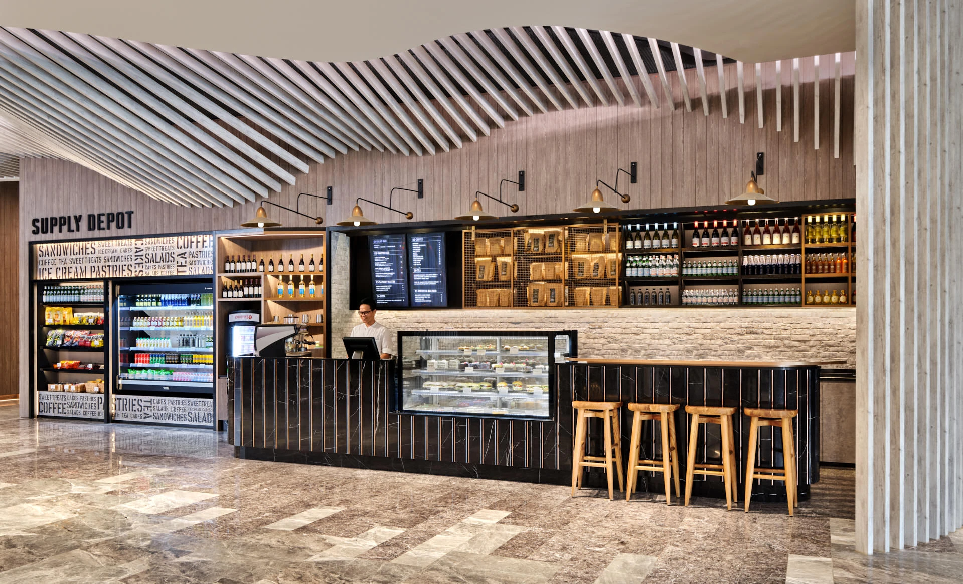 Barista at Supply Depot counter with espresso machine and pastry display — Village Hotel Singapore hotel photography