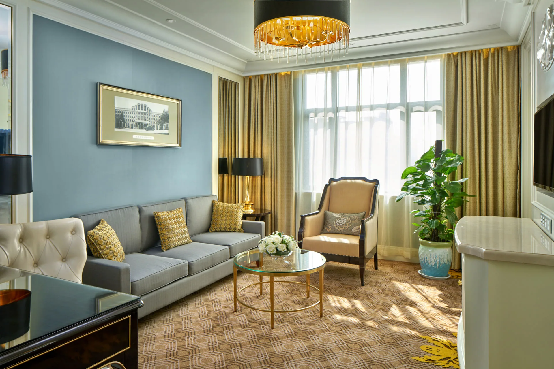 Suite living room with powder-blue walls, brass table and gold pendants — Crowne Plaza Zhengzhou interior photography