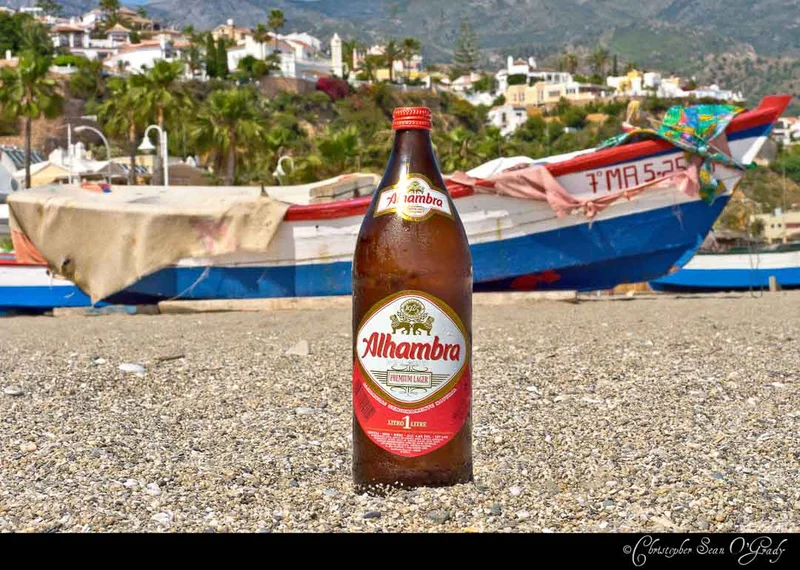 Alhambra Premium Lager 1-litre bottle on a Spanish beach with fishing boat