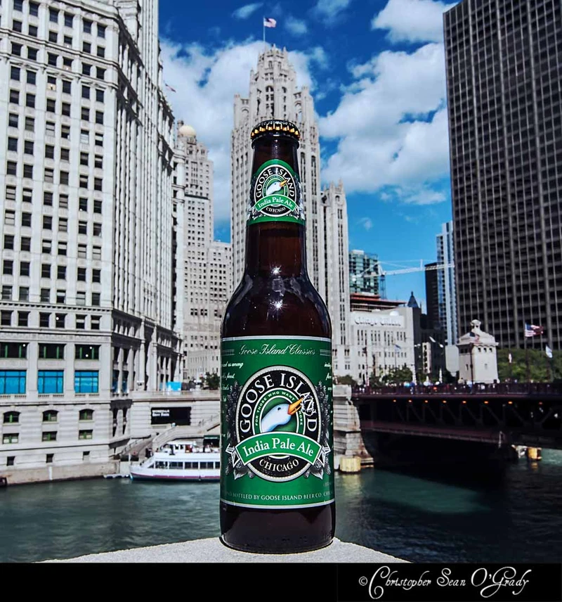 Goose Island India Pale Ale bottle on a ledge with Chicago River and skyline