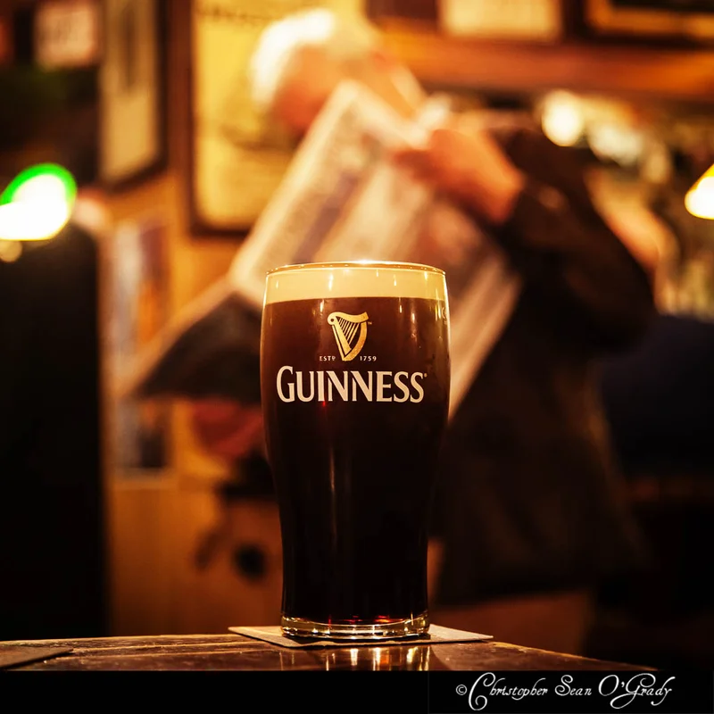 Guinness pint on a wooden bar in a warm dimly lit Irish pub
