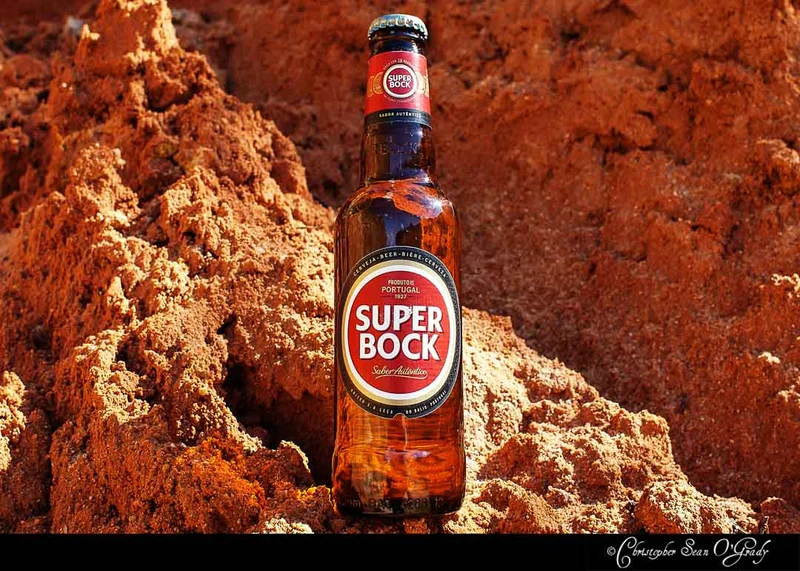 Super Bock beer bottle nestled in sunlit red sandstone cliff formations